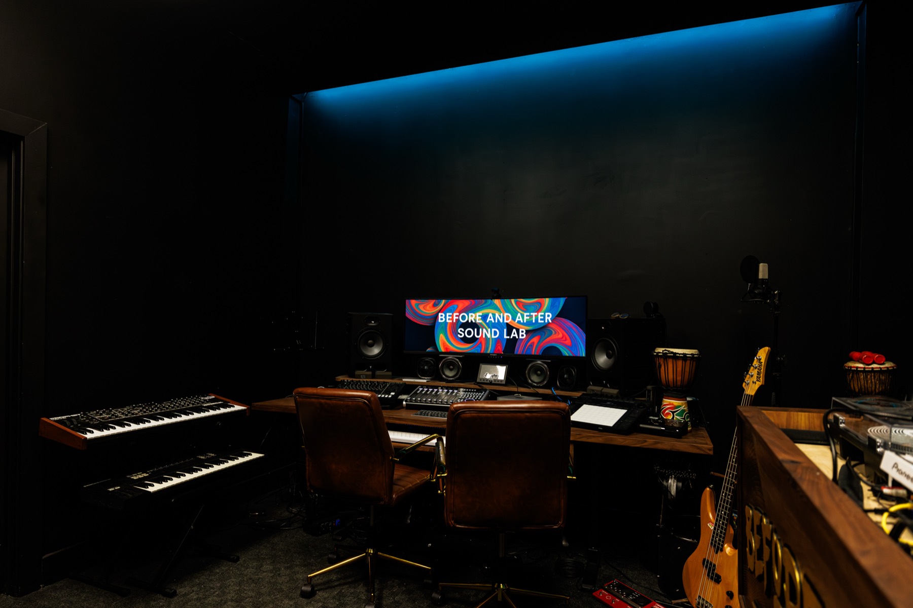 The production desk, studio monitors either side of an ultrawide screen